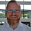 Portraitfoto von Matthias Wolf in Businesskleidung lachend mit Brille 