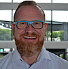 Portraitfoto von Matthias Wolf in Businesskleidung lachend mit Brille
