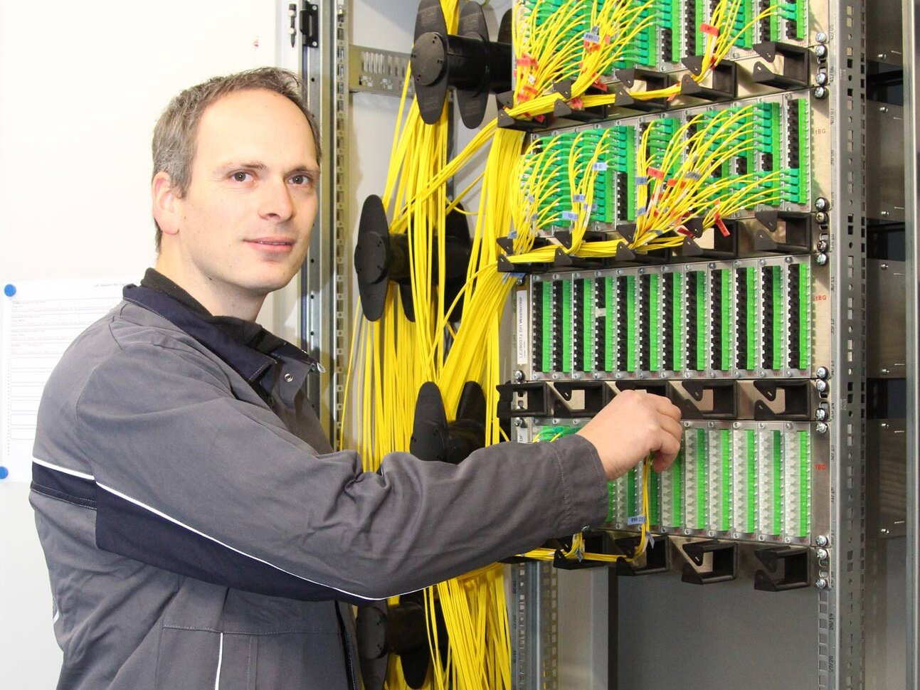 WWN Telekommunikationsdienstleistungen Mann steht vor einem Lichtwellenleiter Verteiler