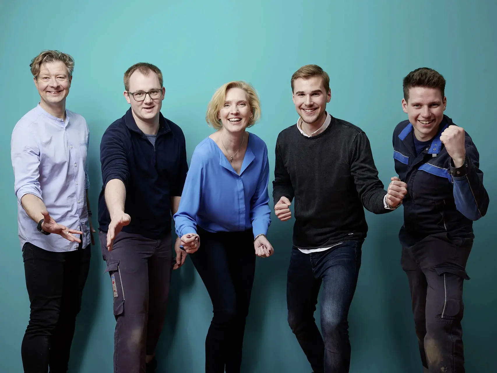 WW Bewerber Gruppenbild von motivierten Personen vor einem petrolfarbenen Hintergrund