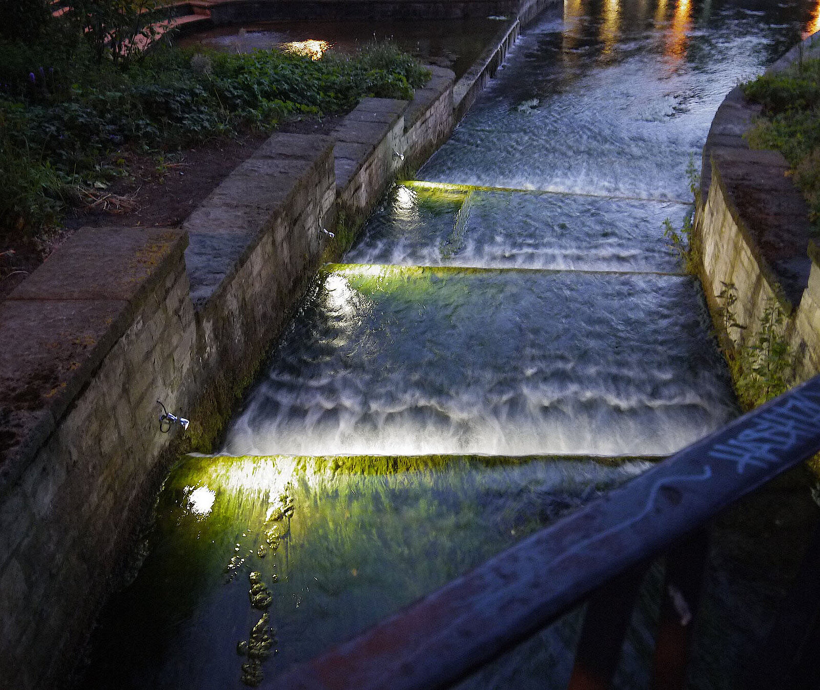 Beleuchtete Flussstufen im Paderquellgebiet bei Nacht