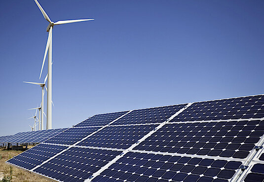 Solar-Panel mit Windrädern im Hintergrund