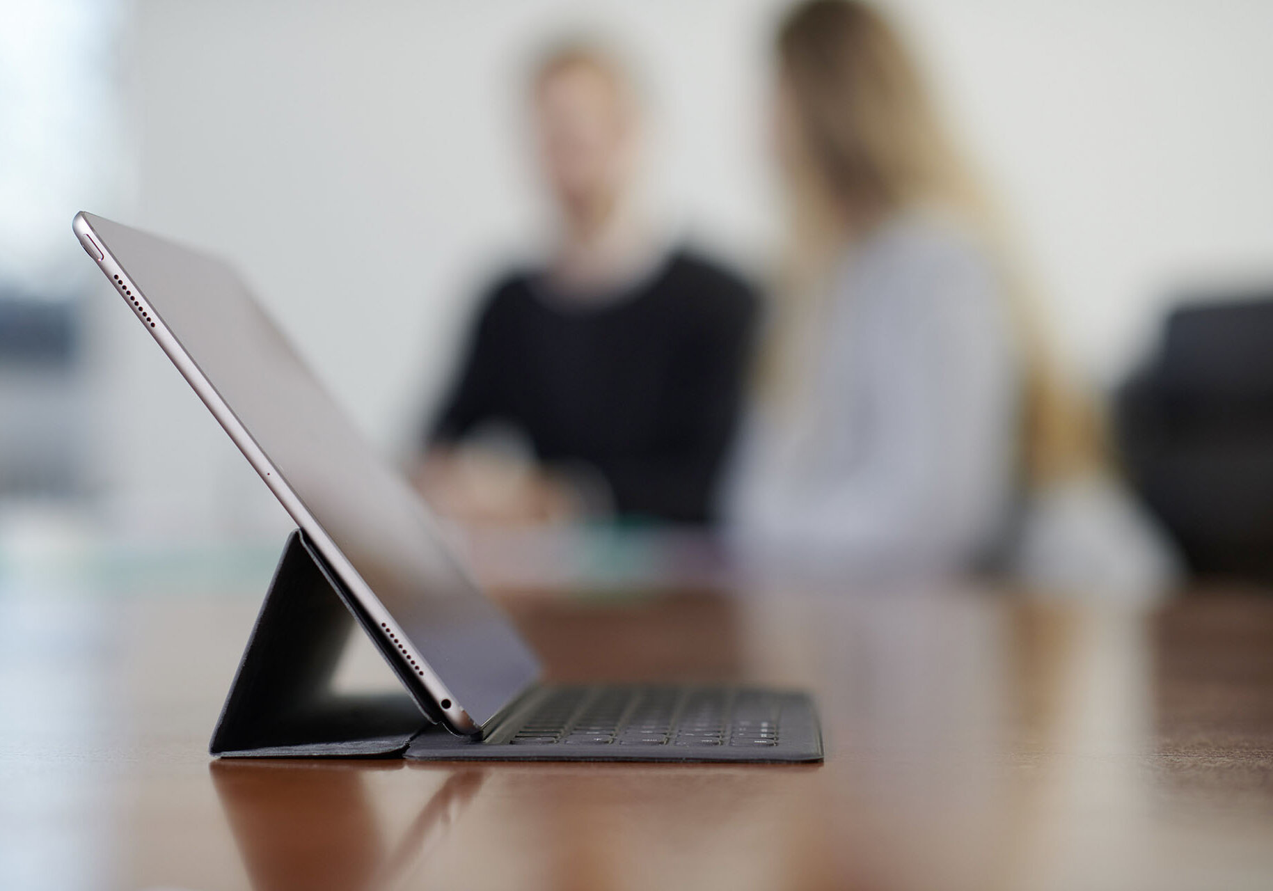 WWN Anmelden Abmelden Tablet auf einem Tisch mit Mitarbeitern unscharf im Hintergrund