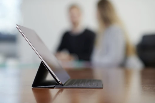 Tablet auf einem Tisch mit Mitarbeitern unscharf im Hintergrund
