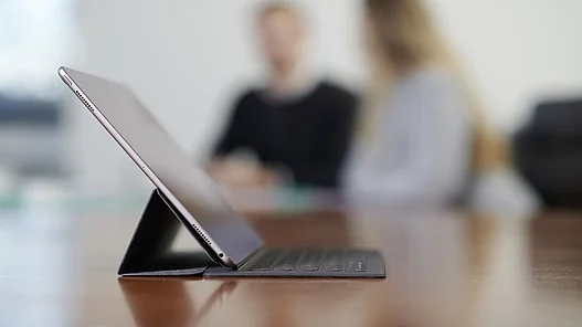 WWN Anmelden Abmelden Tablet auf einem Tisch mit Mitarbeitern unscharf im Hintergrund