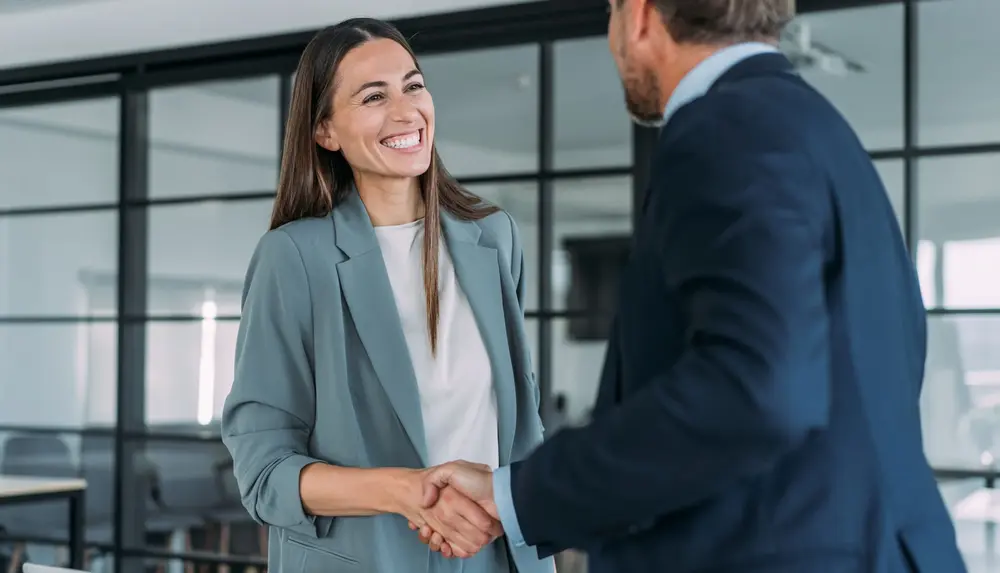 Zwei Personen geben sich in einem modernen Büro die Hand während eines Beratungsgesprächs zum Netzanschlussservice.