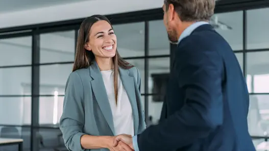 Zwei Personen geben sich in einem modernen Büro die Hand während eines Beratungsgesprächs zum Netzanschlussservice.