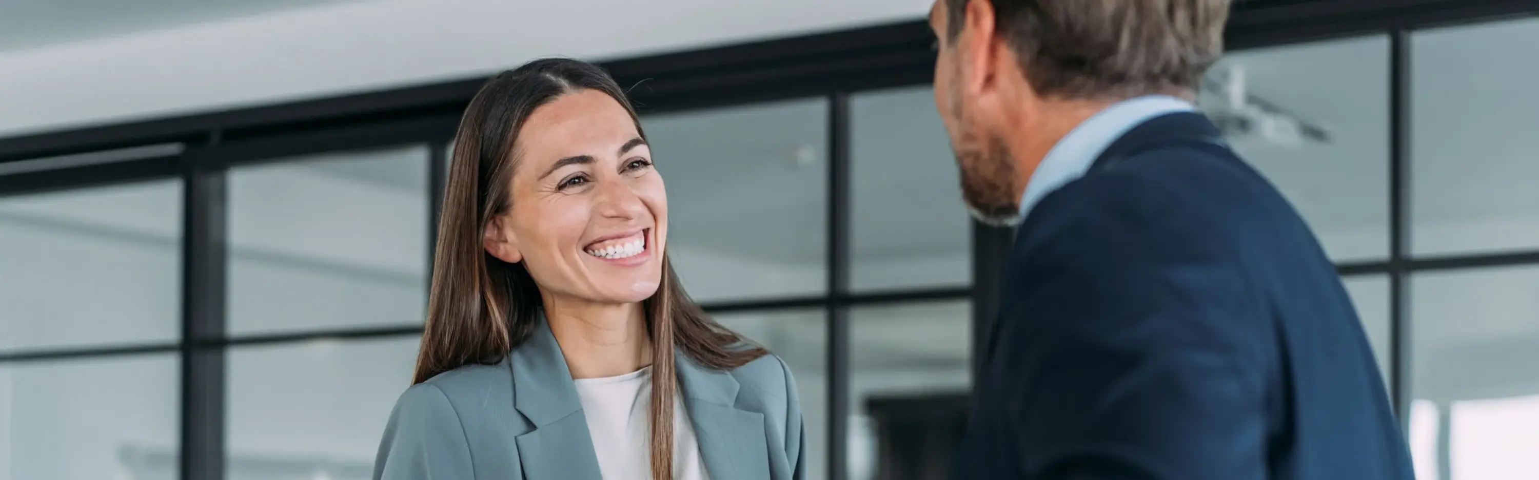 Zwei Personen geben sich in einem modernen Büro die Hand während eines Beratungsgesprächs zum Netzanschlussservice.