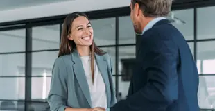 Zwei Personen geben sich in einem modernen Büro die Hand während eines Beratungsgesprächs zum Netzanschlussservice.