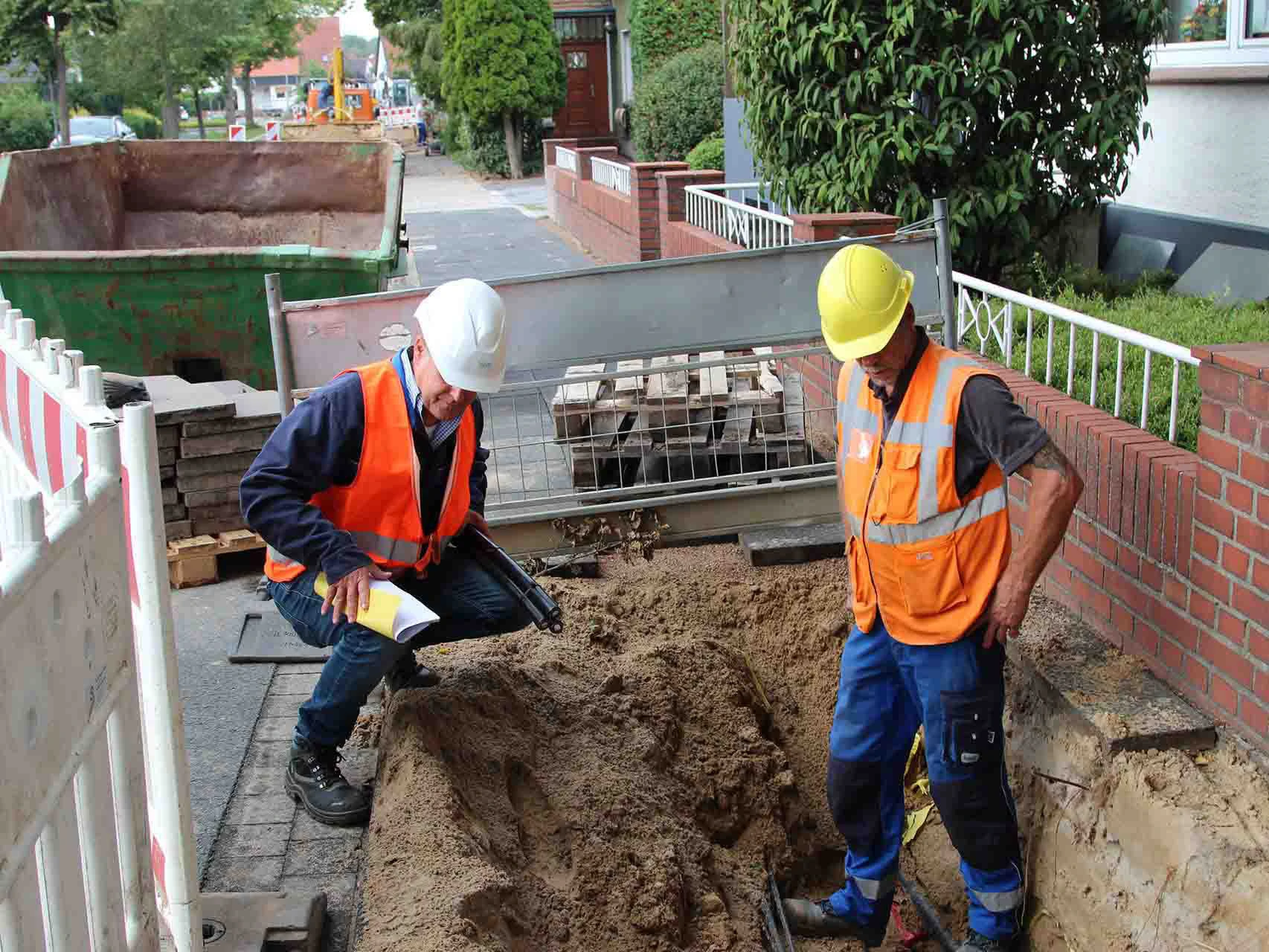 WW Bauherren Monteure verlegen Bodenleitungen in einer Baustelle