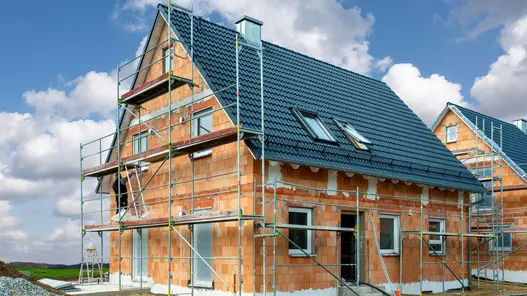 Einfamilienhaus im Rohbau mit Ziegeldach und Baugerüst