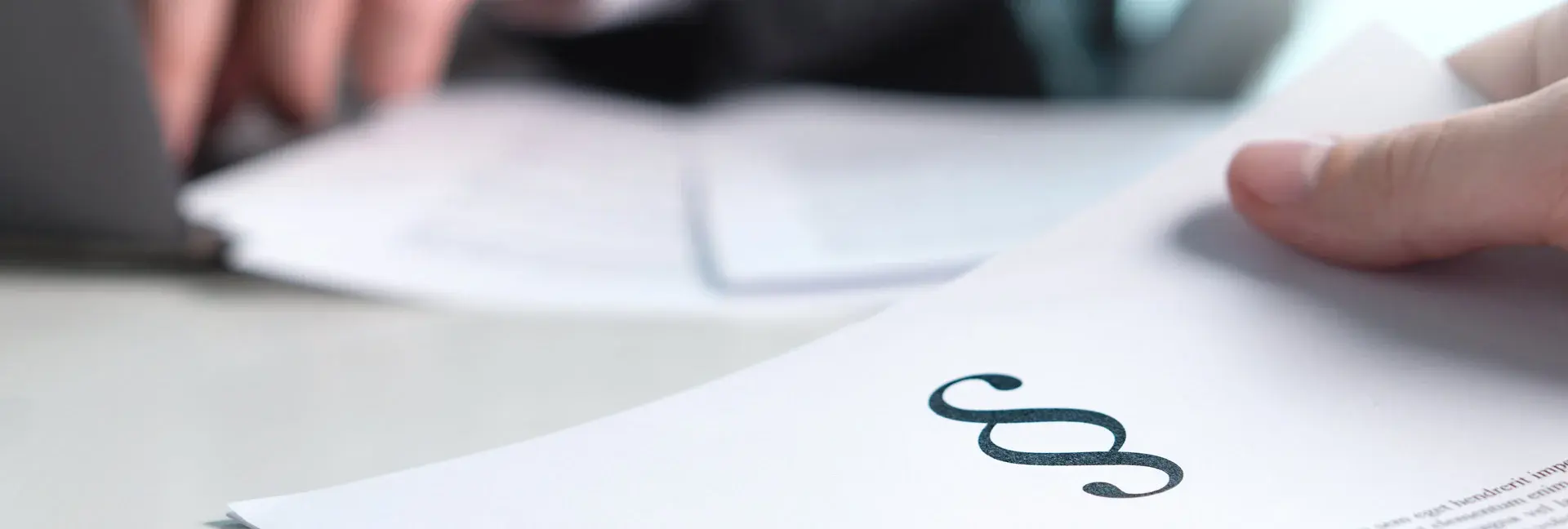 Hände und ein Zettel mit einem Paragraphensymbol