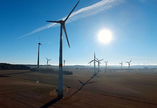 Windräder auf Feldern mit scheinender Sonne