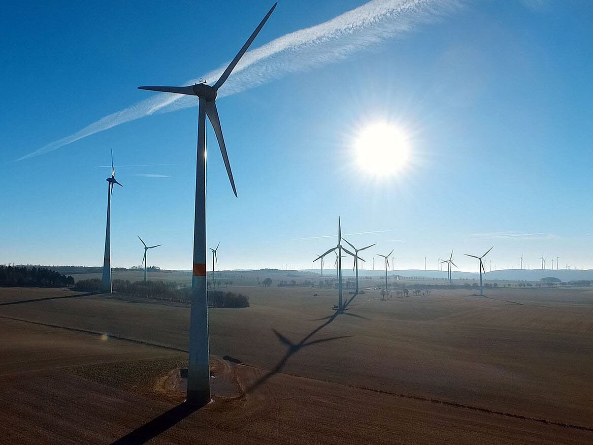 WW CO2 Neutralitaet Windräder auf Feldern mit scheinender Sonne