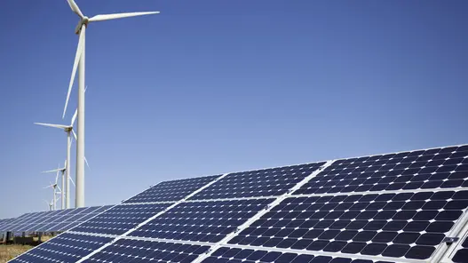 Photovoltaikanlage mit Windrädern im Hintergrund bei blauem Himmel